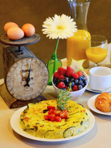 Breakfast Frittata on a table with a mail scale and fresh fruit and eggs.