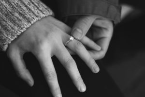 A woman's hand being held by a man slipping on an engagement ring.