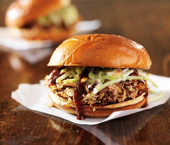 pulled pork sandwich on a bun with cole slaw and bbq sauce